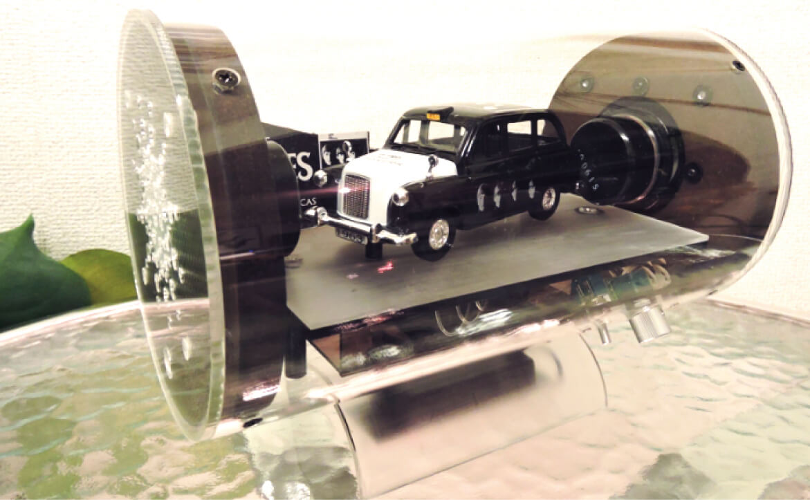 写真：スケルトンスピーカーのカスタムオーダー例、中型(アンプ内蔵型)クラシックカーの模型が入っている